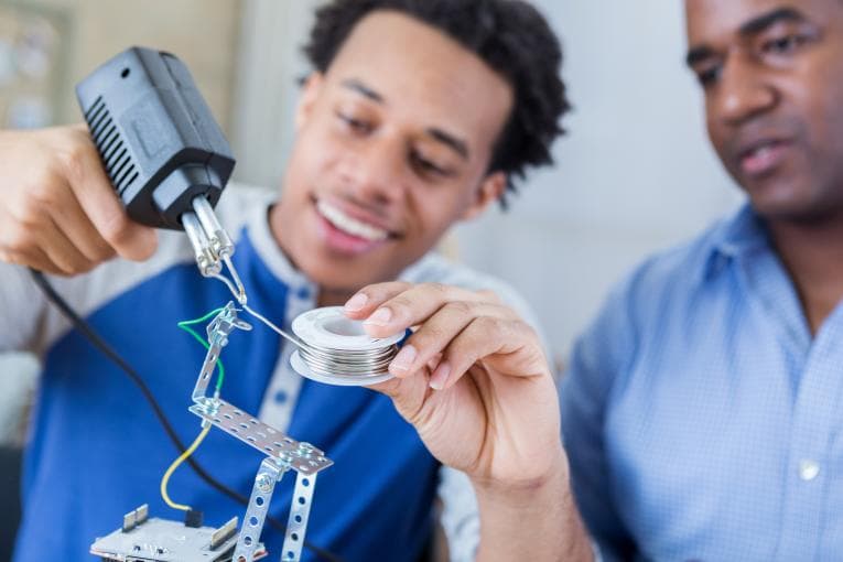 Two people with one holding a soldering device