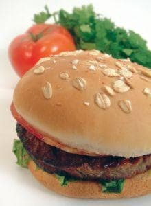 A burger and a tomato with some lettuce