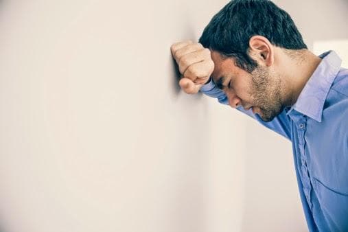 Stressed man leaning on wall
