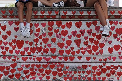 Children sit on the Covid memorial wall