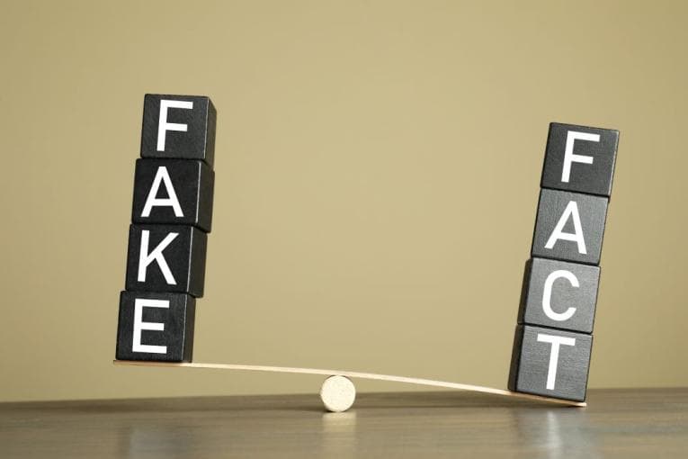 A seesaw with 'fact' and 'fake' balancing at either end