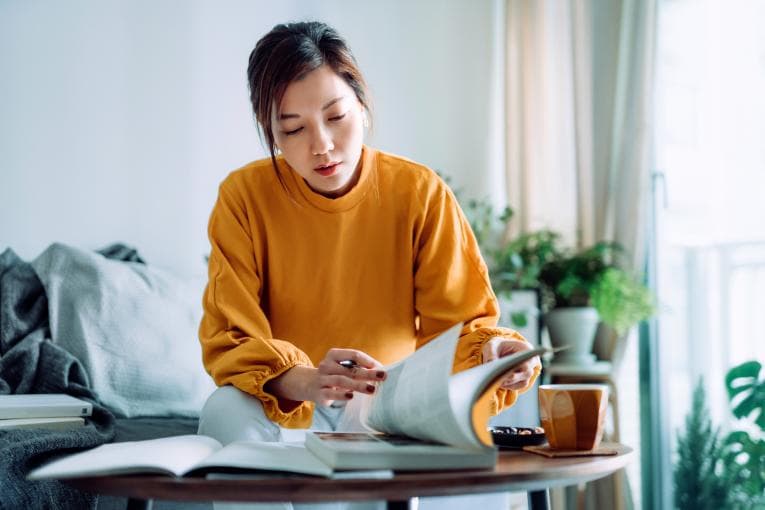 A woman looks at books on a coffee table